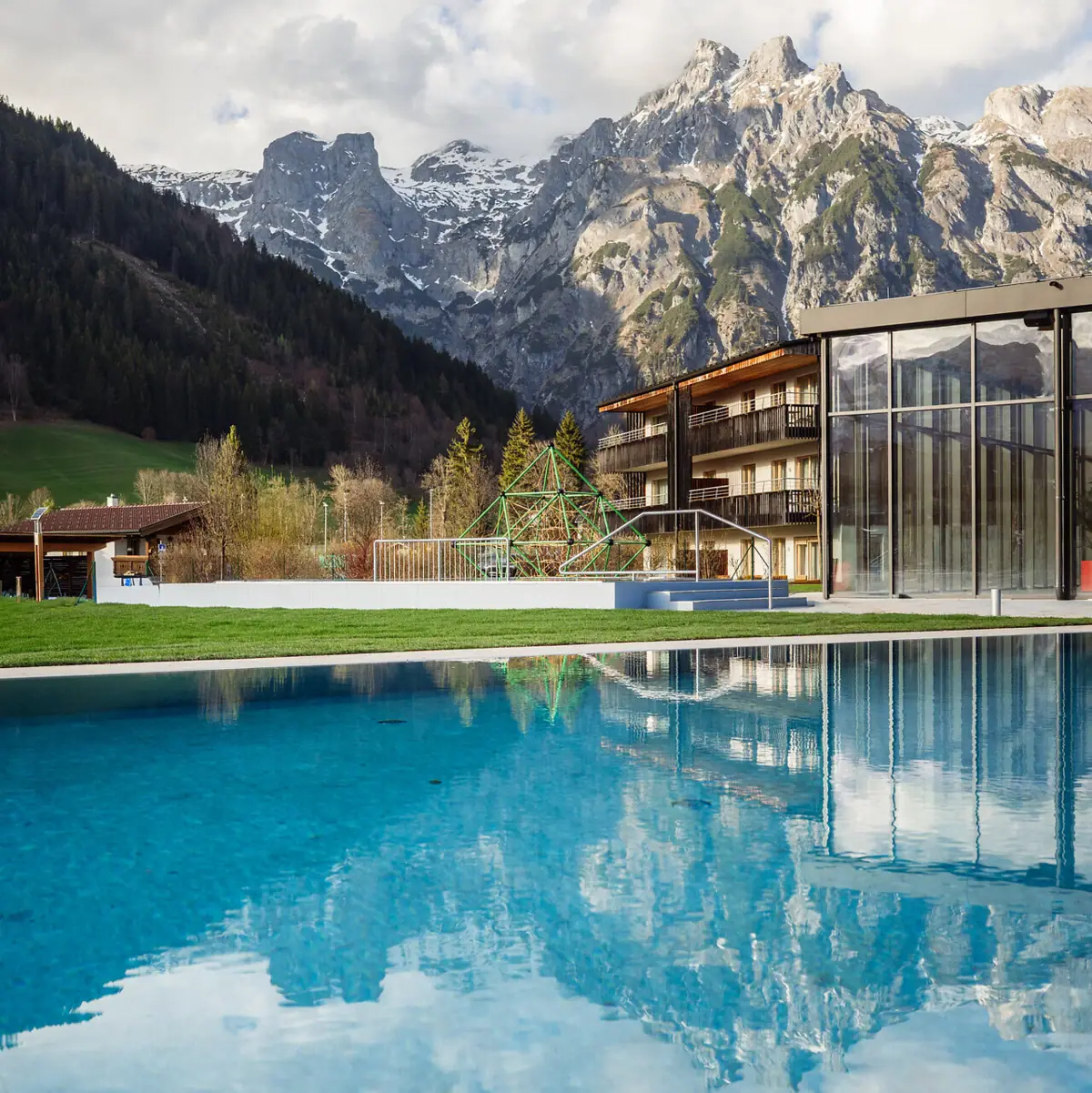 Ein Außenpool im Schwimmbad Werfenweng mit Bergen im Hintergrund.