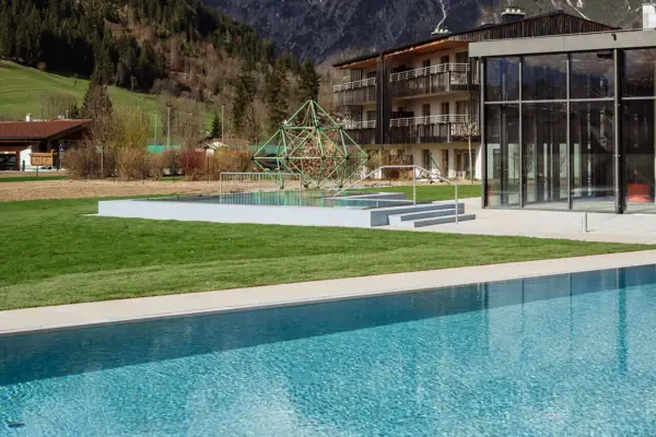 Außenpool mit Gebäude im Hintergrund und umliegenden Bergen.