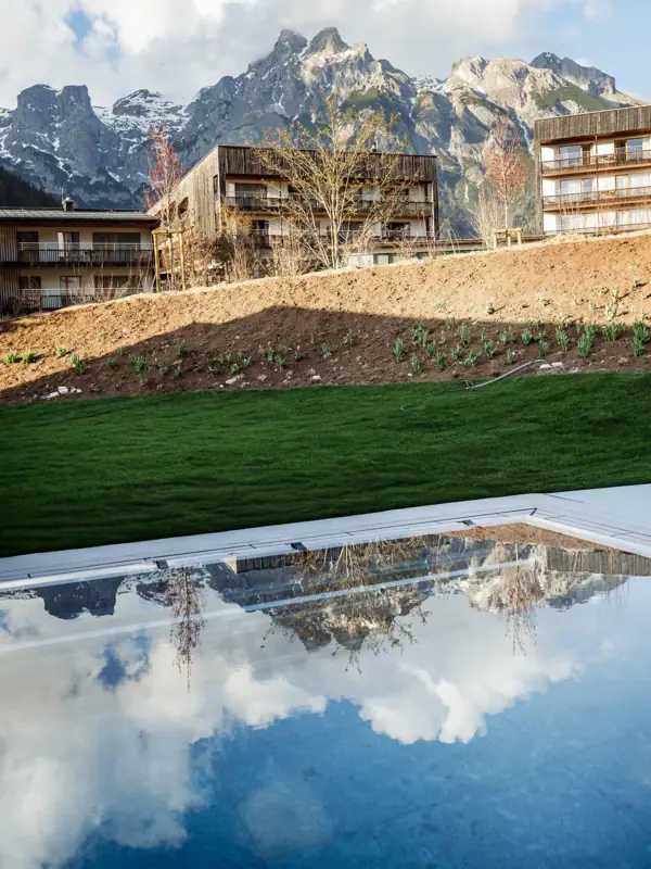 Ein Pool neben Gebäuden und Bergen.