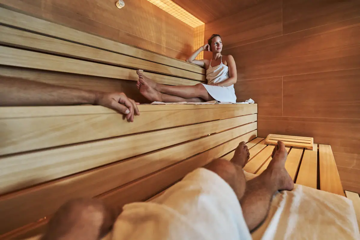 Sauna Eine Frau sitzt auf einer Holzbank in einer Sauna im Badehaus Werfenweng.
