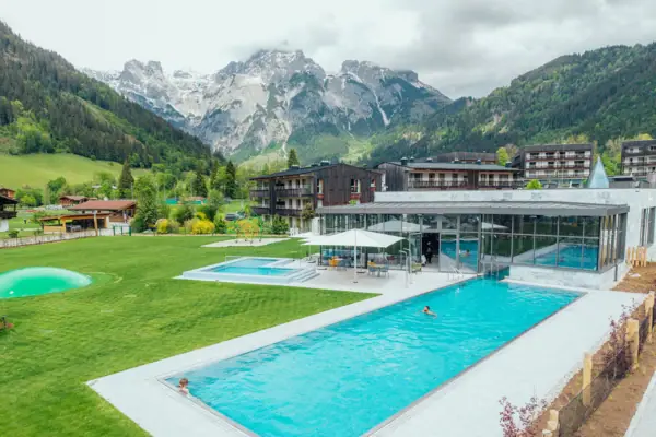 Schwimmbecken mit einem Gebäude und Bergen im Hintergrund.